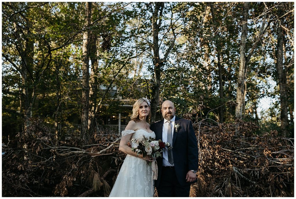 A couple stands in front of debris before their intimate backyard wedding