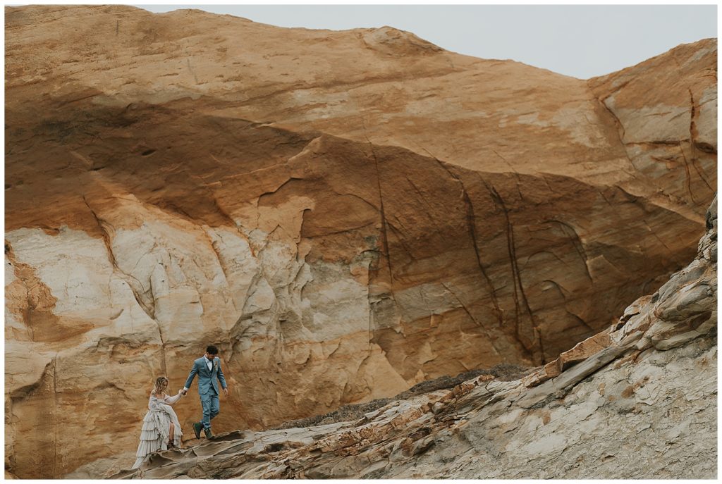 A couple walks along the Cape Kiwanda sandstone cliffs at their wedding on oregon coast