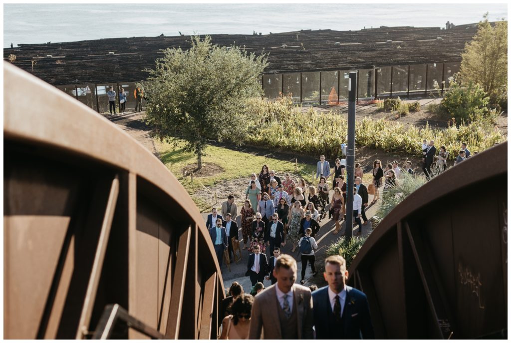 The grooms lead their guests over the bridge at the Tigermen Den wedding