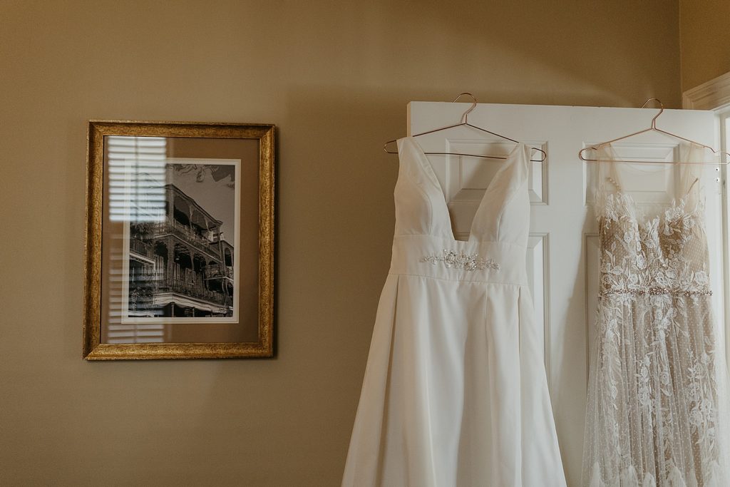 Two wedding dresses hang on a door.