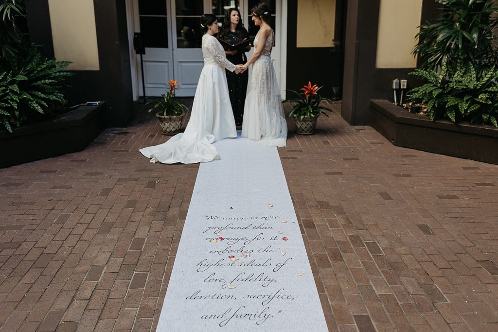 Brides stand at the top of a hand painted runner.