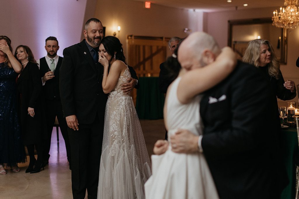 One bride cries as the other dances with her father.