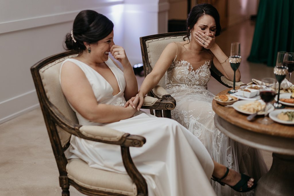 The brides sit at the sweetheart table.