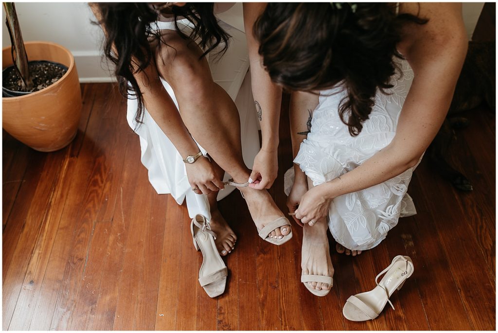 Two brides fasten their shoes.
