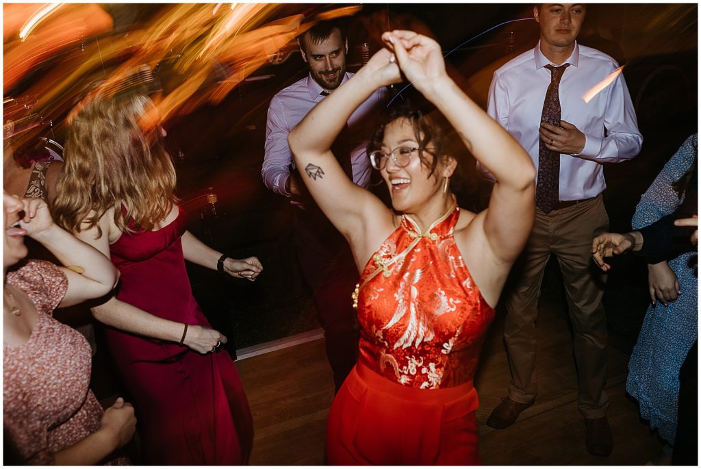 A woman in a red jumpsuit turns on the dance floor.