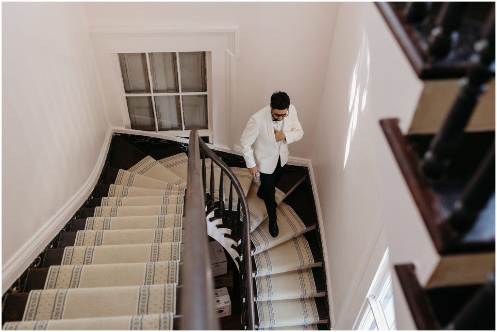 A man in a white jacket walks down a tiled staircase.