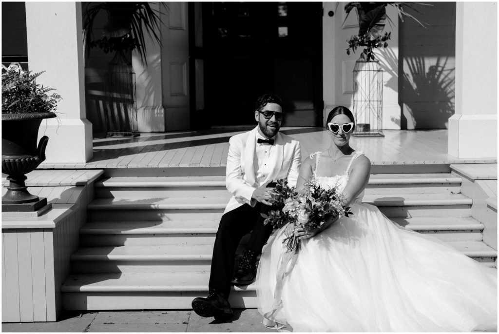 Two people sit on steps in wedding clothes.