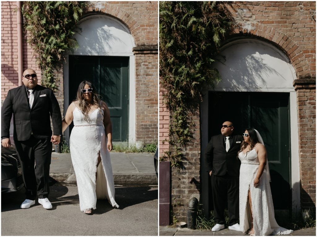 A bride and groom walk in front of a brick building with ivy.