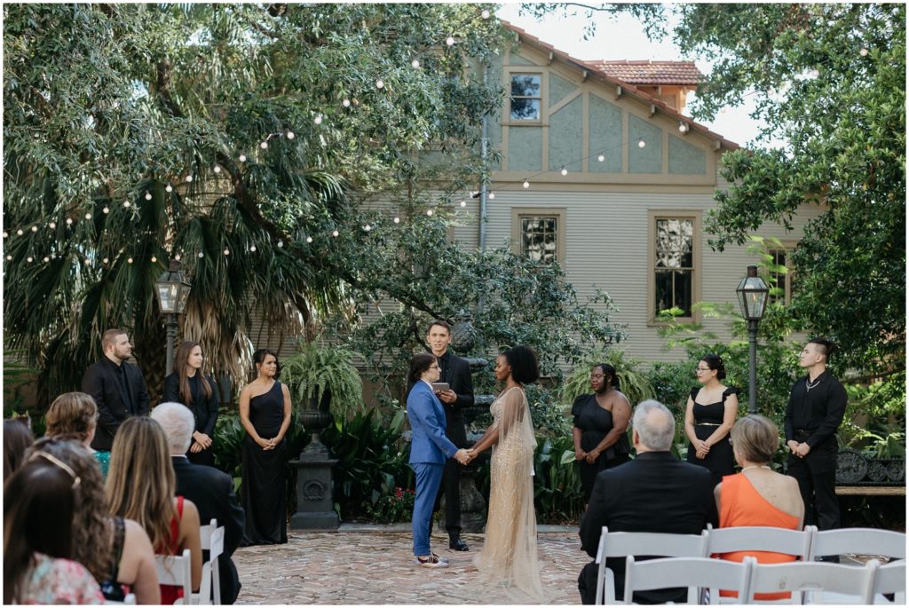 Alex and Isatu hold hands at their Degas House wedding in the New Orleans courtyard.