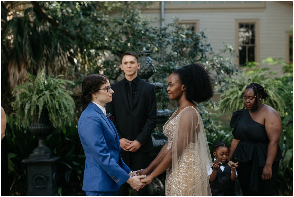 At a New Orleans wedding, a couple holds hands in a courtyard.