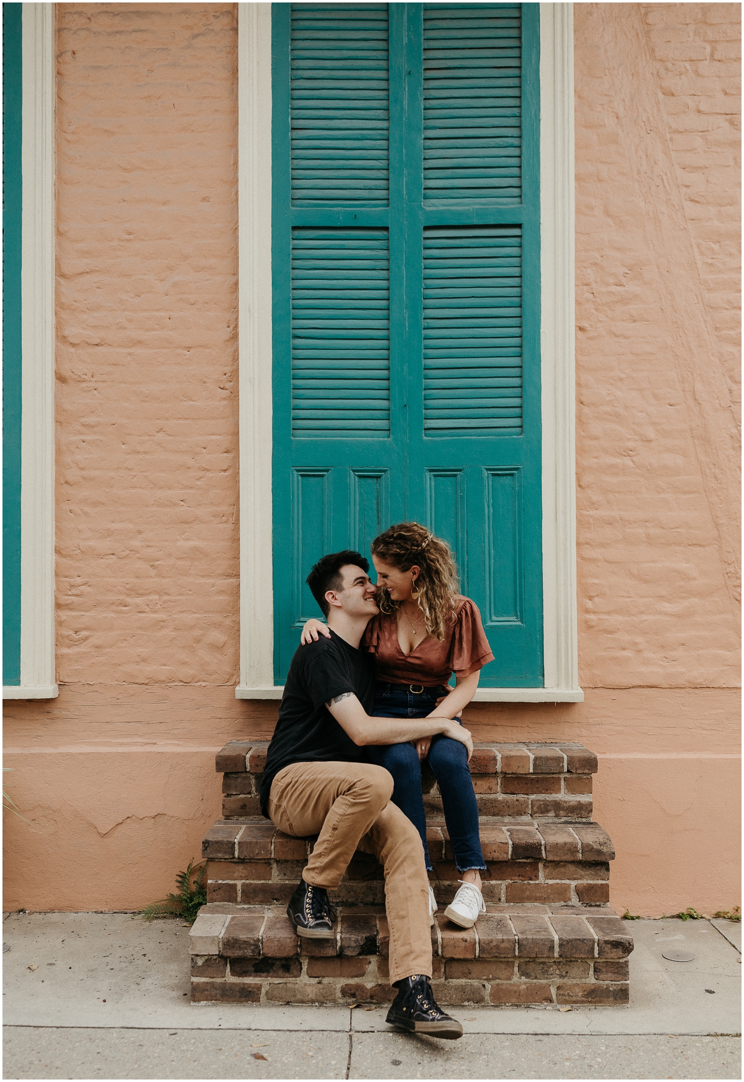 A couple sits on the steps of a New Orleans engagement photo location in the French Quarter.
