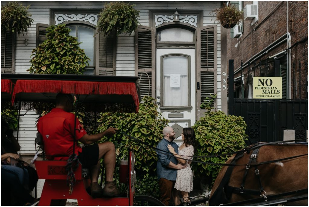A horse drawn carriage passes a couple at their New Orleans engagement session.