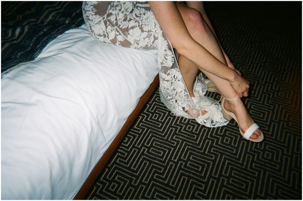 A film wedding photo shows a bride putting on her shoe.