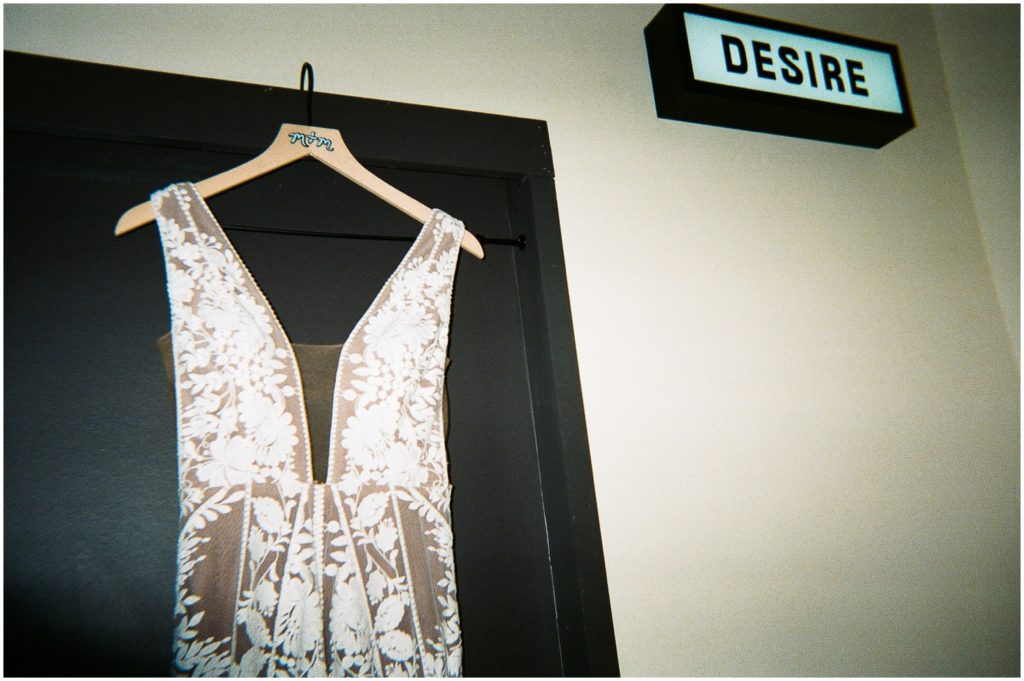 A wedding dress hangs near a sign that sign that says "Desire" before a New Orleans wedding.