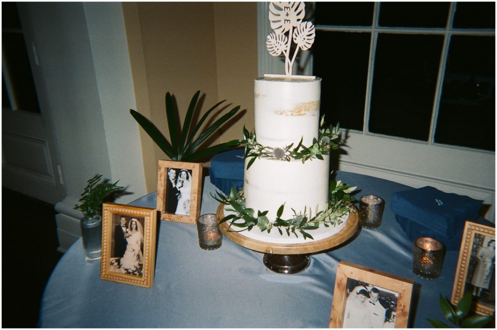 A wedding cake sits in the corner surrounded by wedding photos.