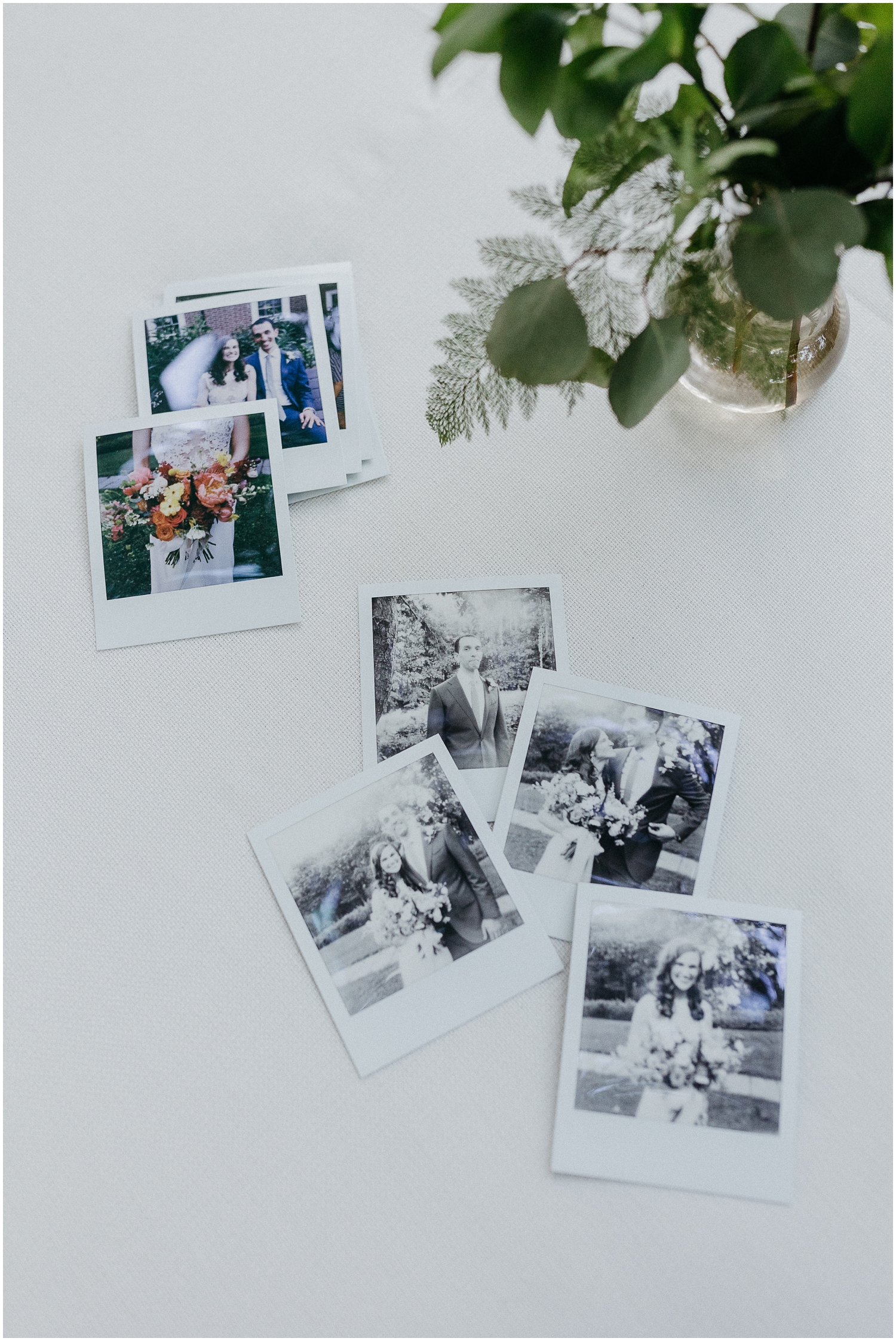 Polaroid wedding photos sit beside a floral arrangement.