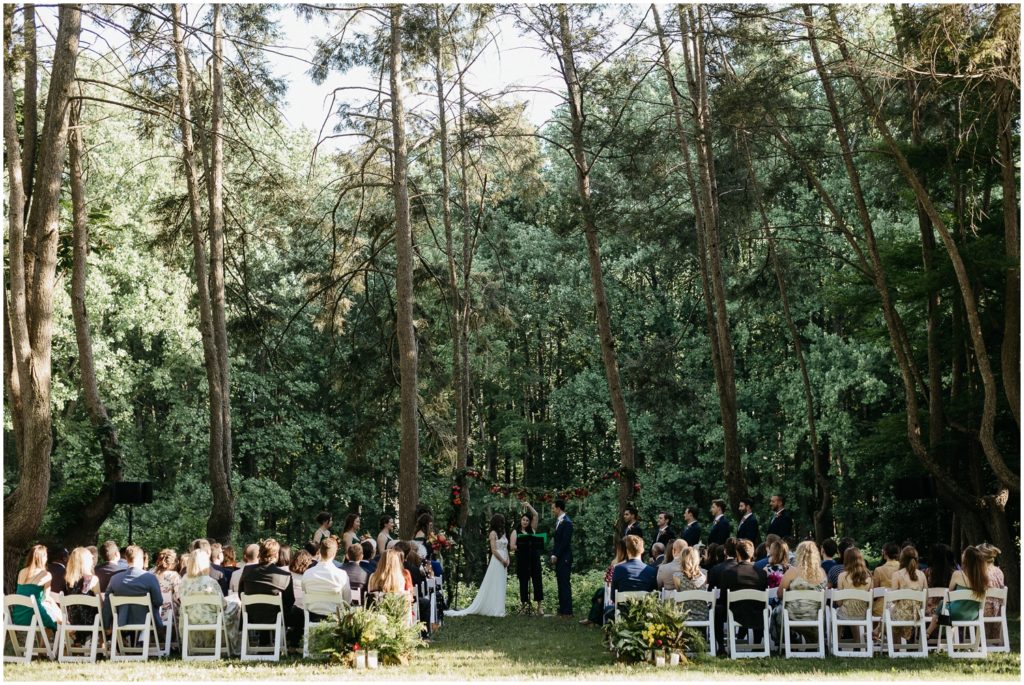 Guests sit in white chairs for the wedding ceremony.
