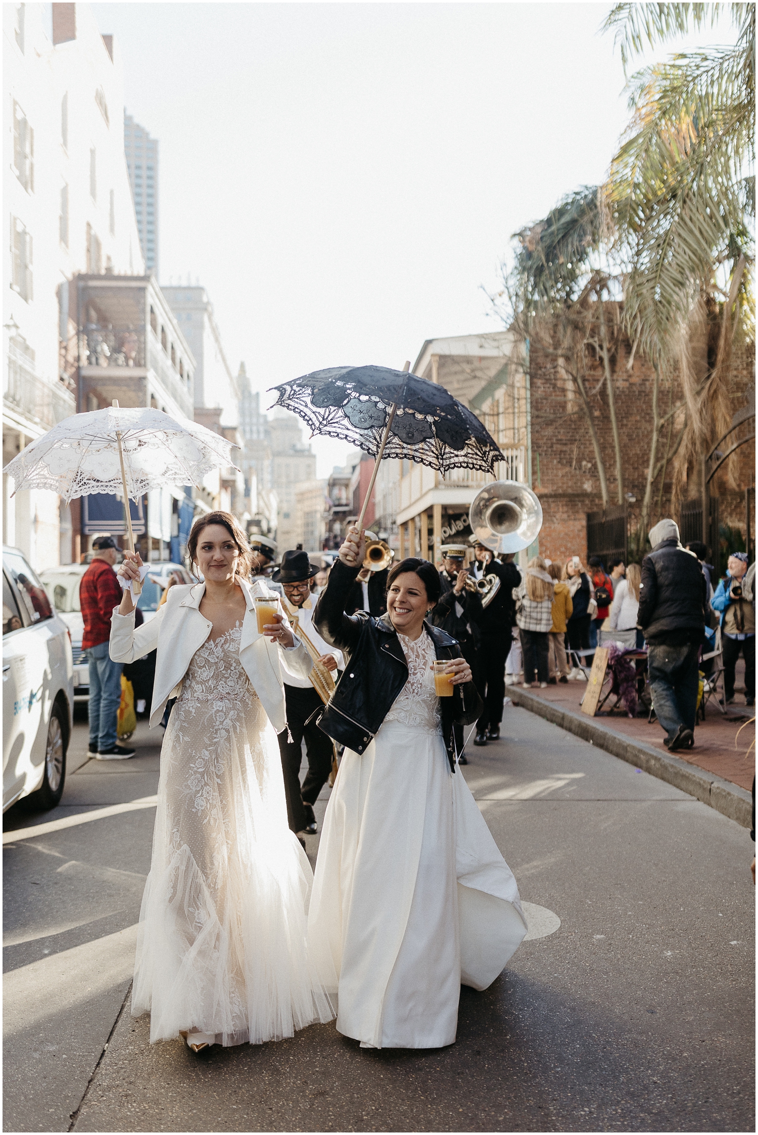 Two brides dance in front of a New Orleans second line at their wedding.