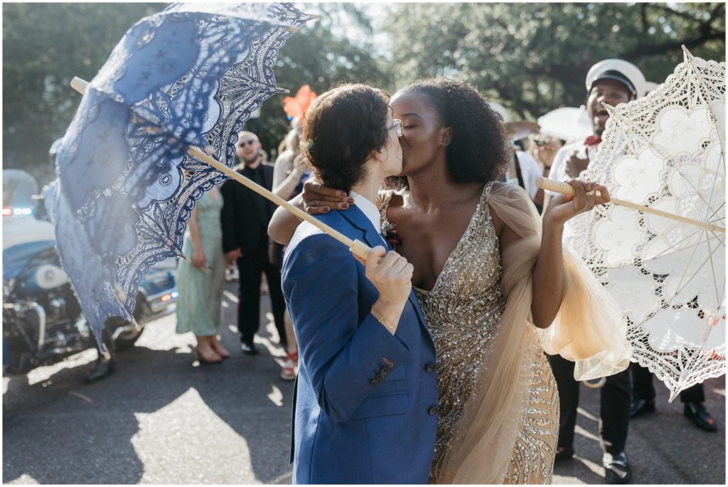 A couple kisses in front of their wedding parade.