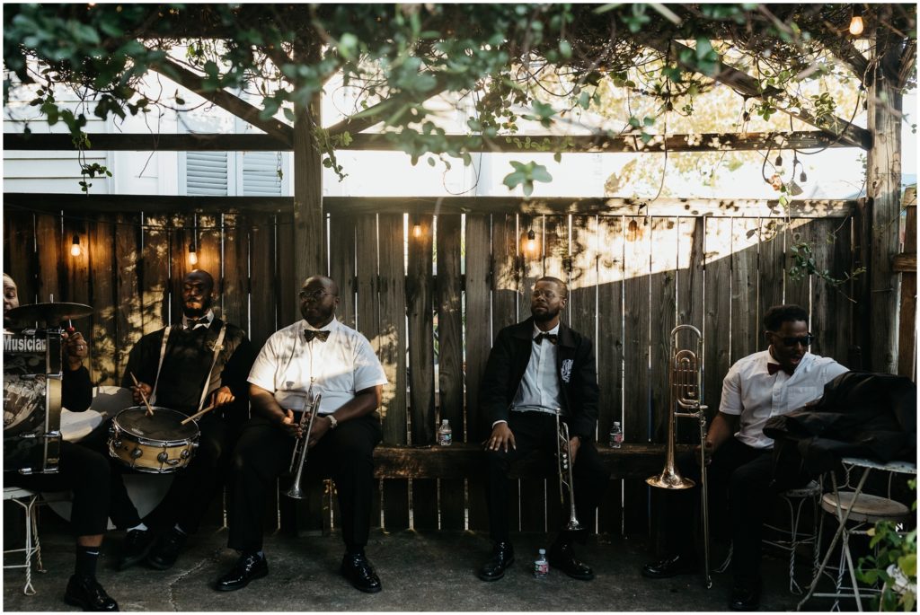 A brass band lines up against a fence at a wedding reception.