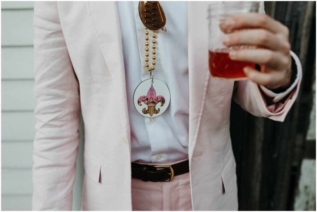A wedding guest wearing Mardi Gras beads holds a cocktail.