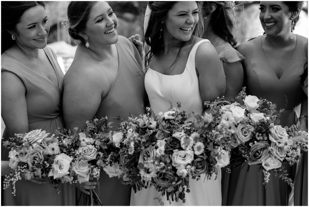 Bridesmaids hold bouquets around Analeah outside the wedding venue.