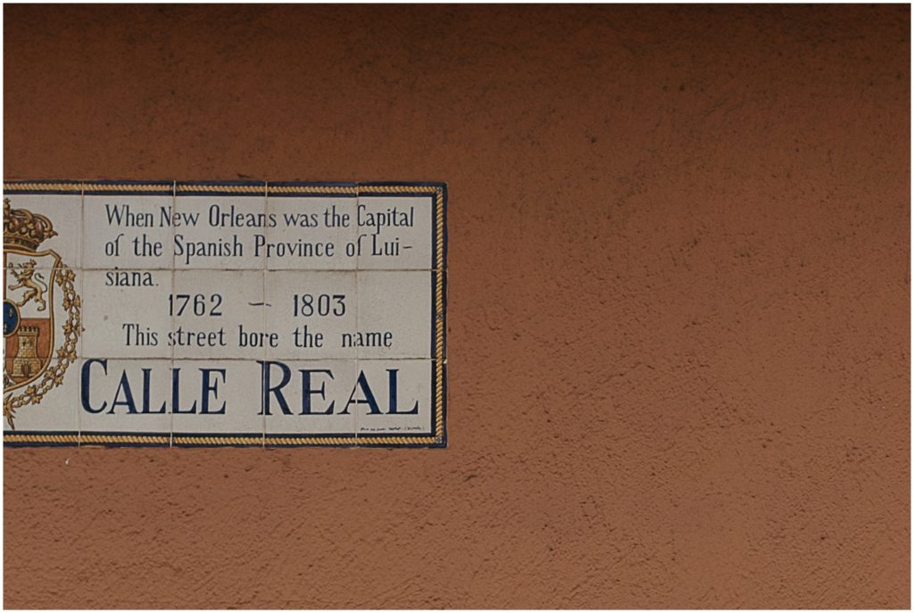 A historical marker describes the history of Royal Street on a pink wall.