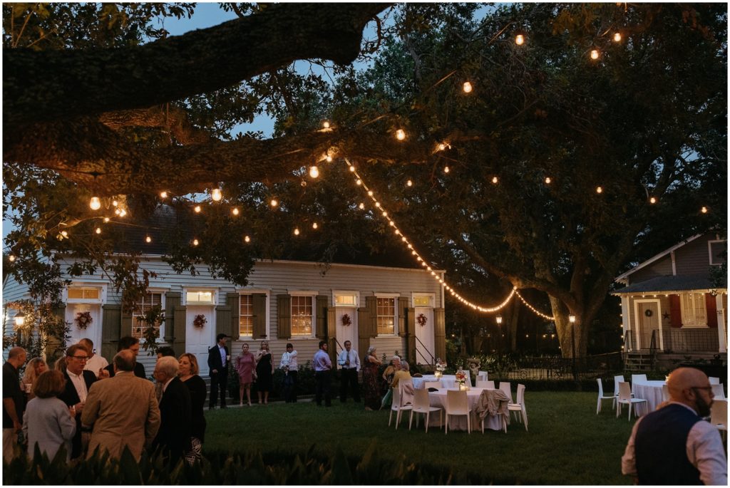Market lights hang from oak trees at a New Orleans destination wedding ceremony.