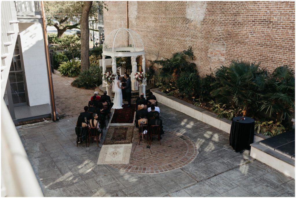 A couple gets married under a white arch at a New Orleans destination wedding.