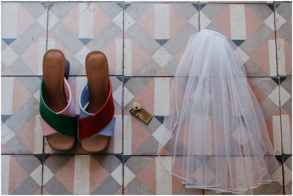 A veil and wedding shoes sit on a blue and pink tiled floor at the Drifter Hotel.
