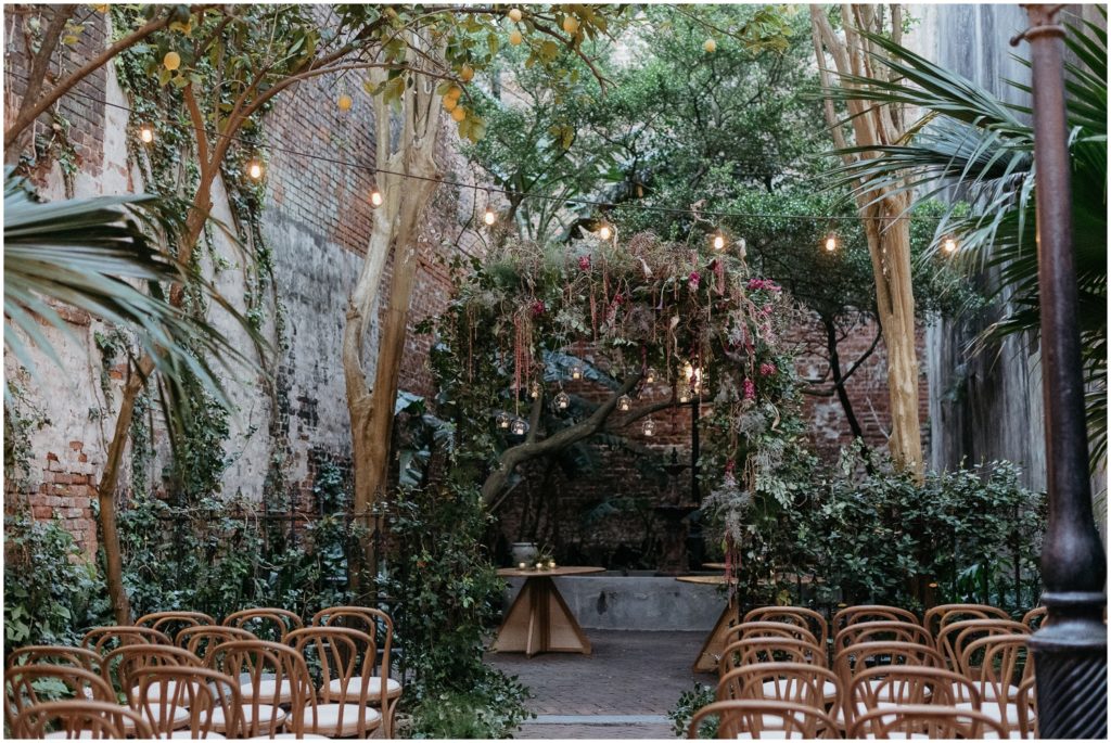 A wedding arch made of greenery and beads decorates the PHarmacy Museum courtyard for a New Orleans destination wedding.