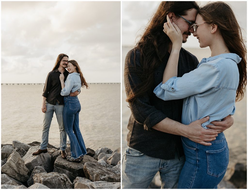 A man and woman wearing denim embrace on boulders on the lakefront.