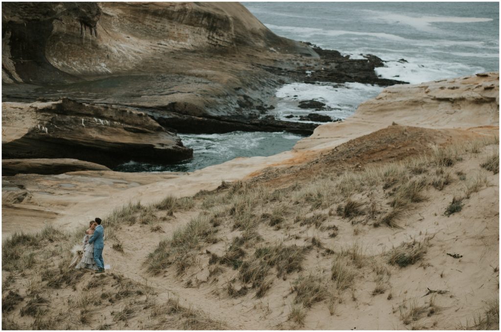 Holly and Steve walk down a path toward the water during their Oregon Coast elopement.