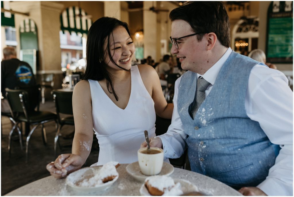 A couple laughs over coffee and beignets at a French Quarter restaurant.