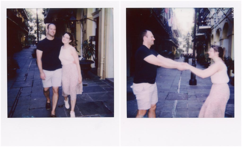 A couple on their honeymoon holds hands and stands in the middle of a street.