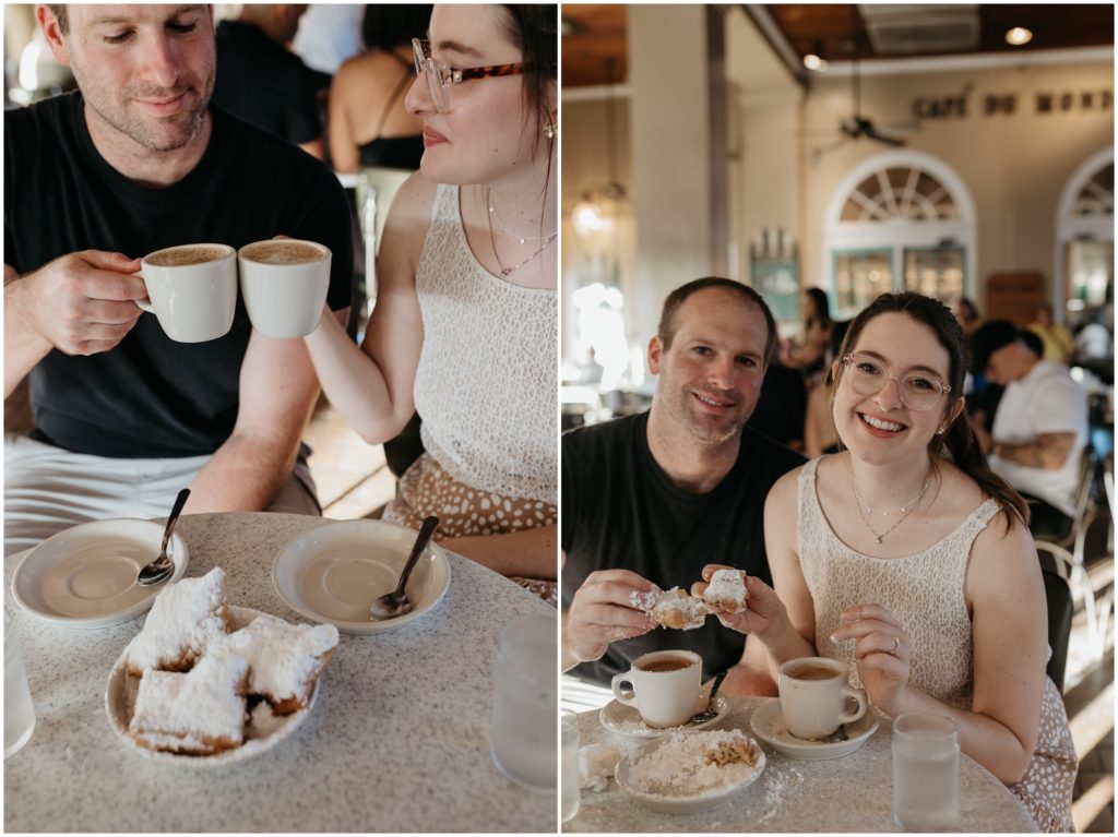 A couple clinks their coffee cups over a plate of beignets.