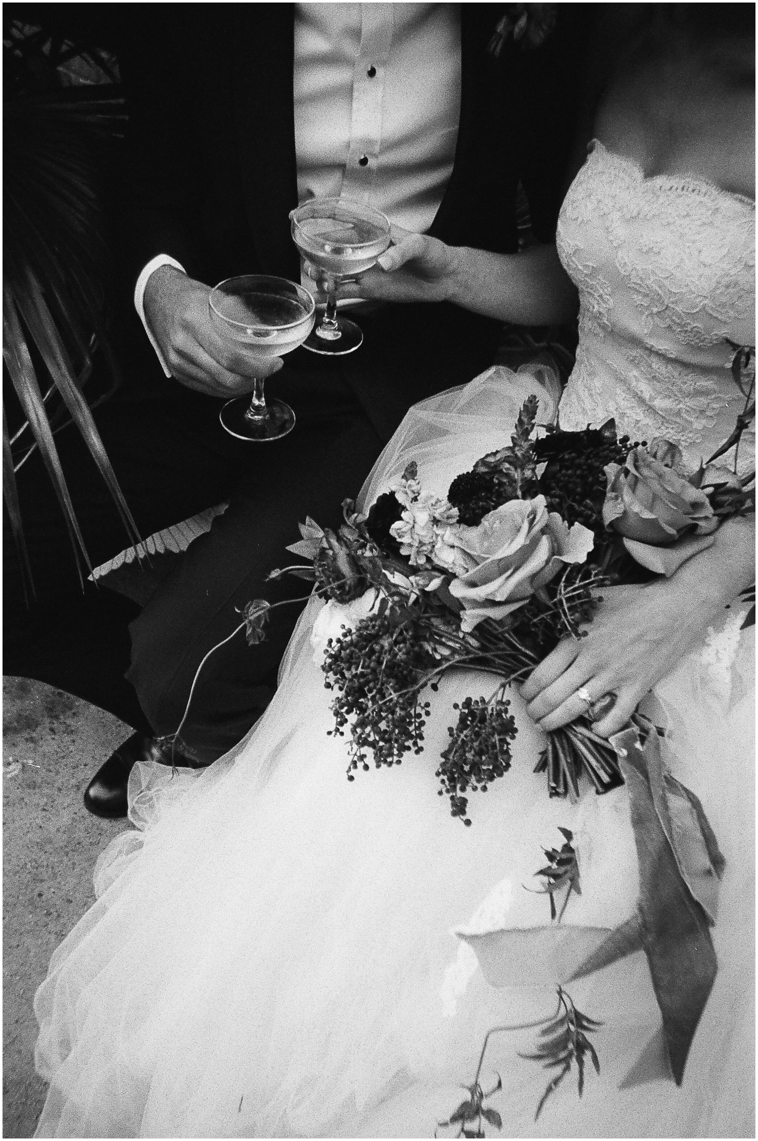A bride hands a groom a cocktail in a black and white image taken on disposable cameras for weddings.