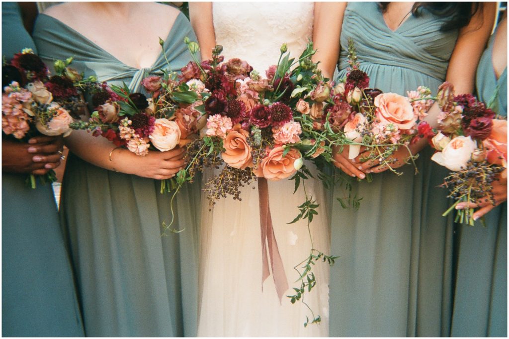 A bride and bridesmaids hold up pink bouquets.