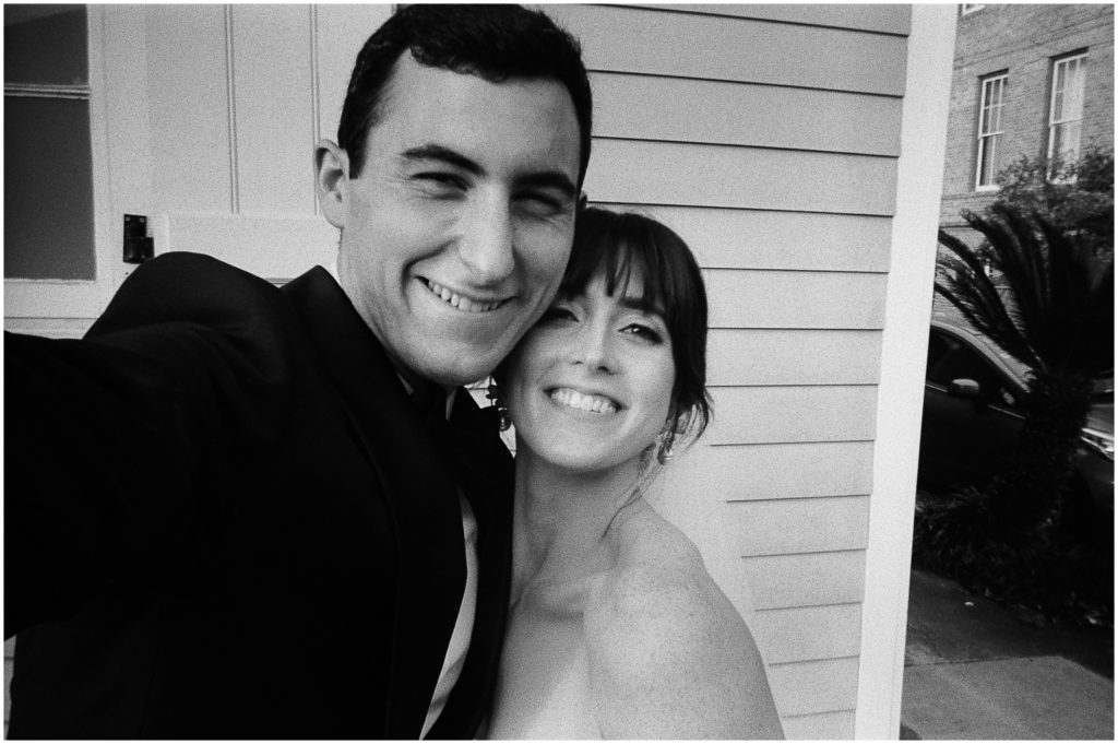 Mary and Steven smile in a black and white selfie beside a white house.