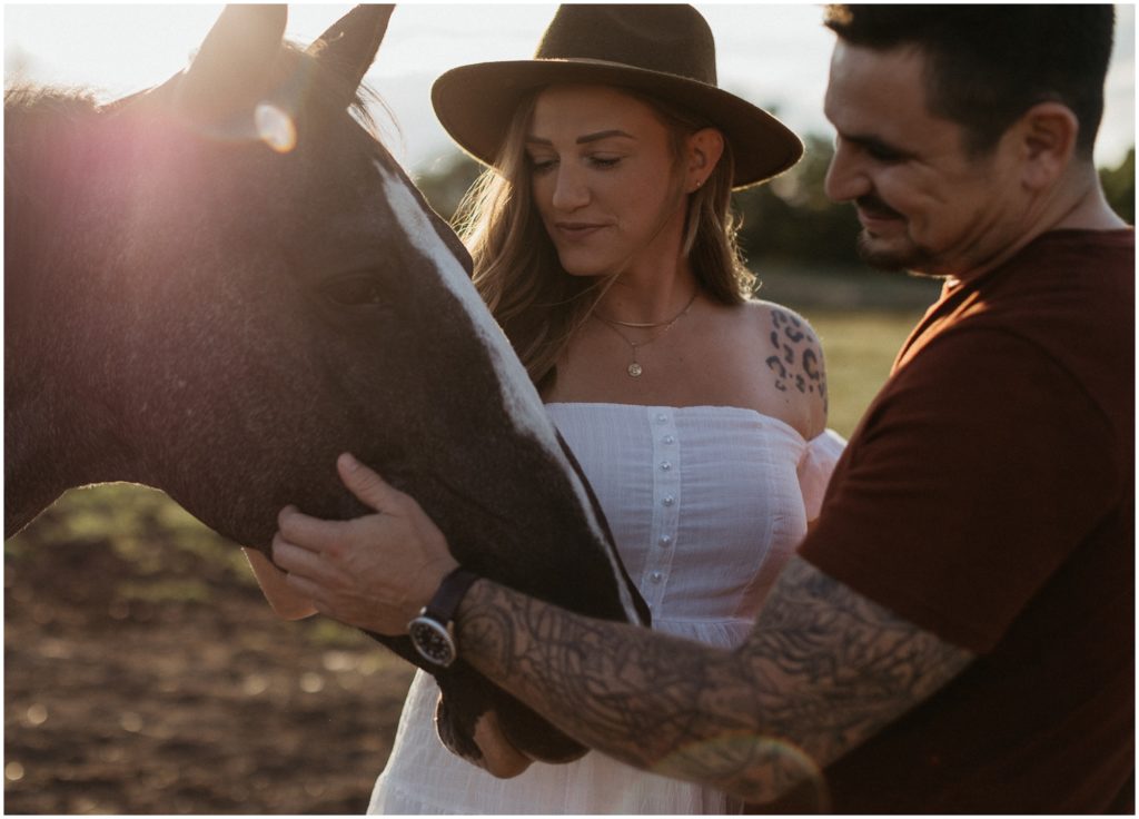 Cara and Alex pet a horse during their maternity session.