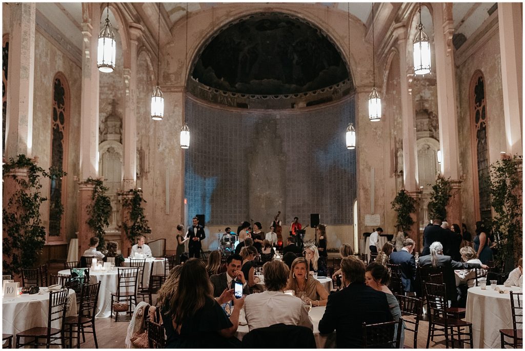 Guests eat dinner in the New Orleans wedding venue while a jazz band plays on stage.