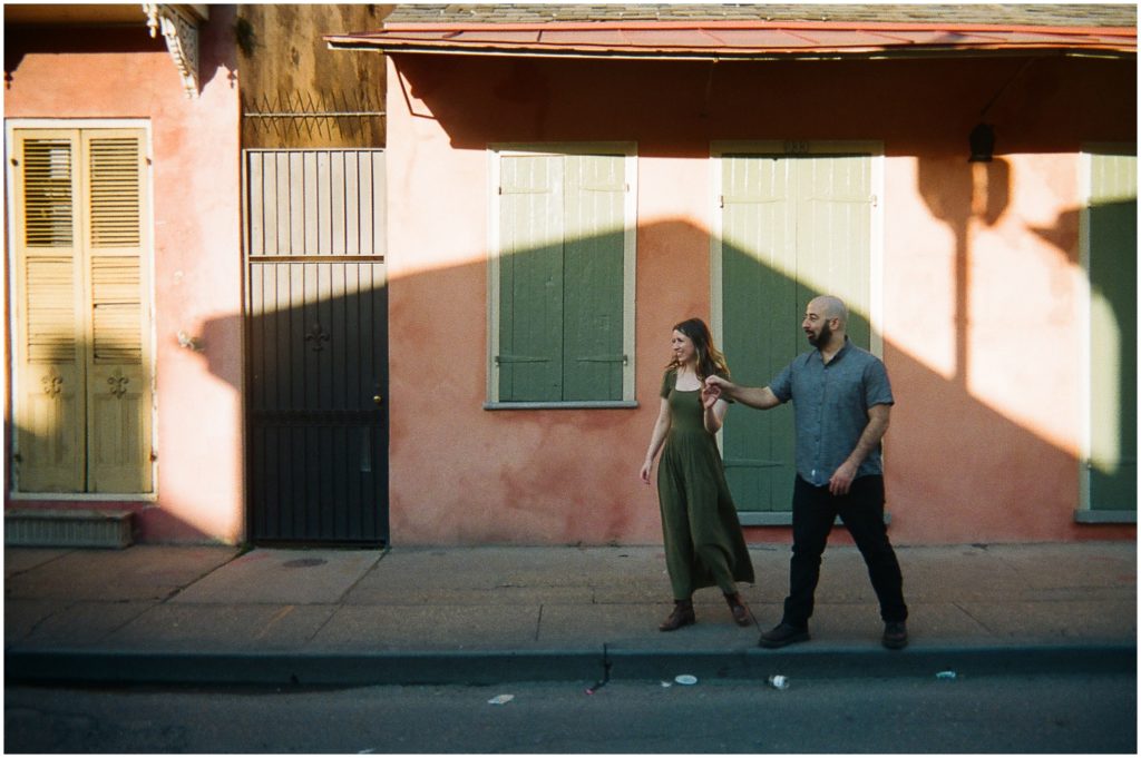 An engaged couple walks through a shadow on a French Quarter sidewalk.