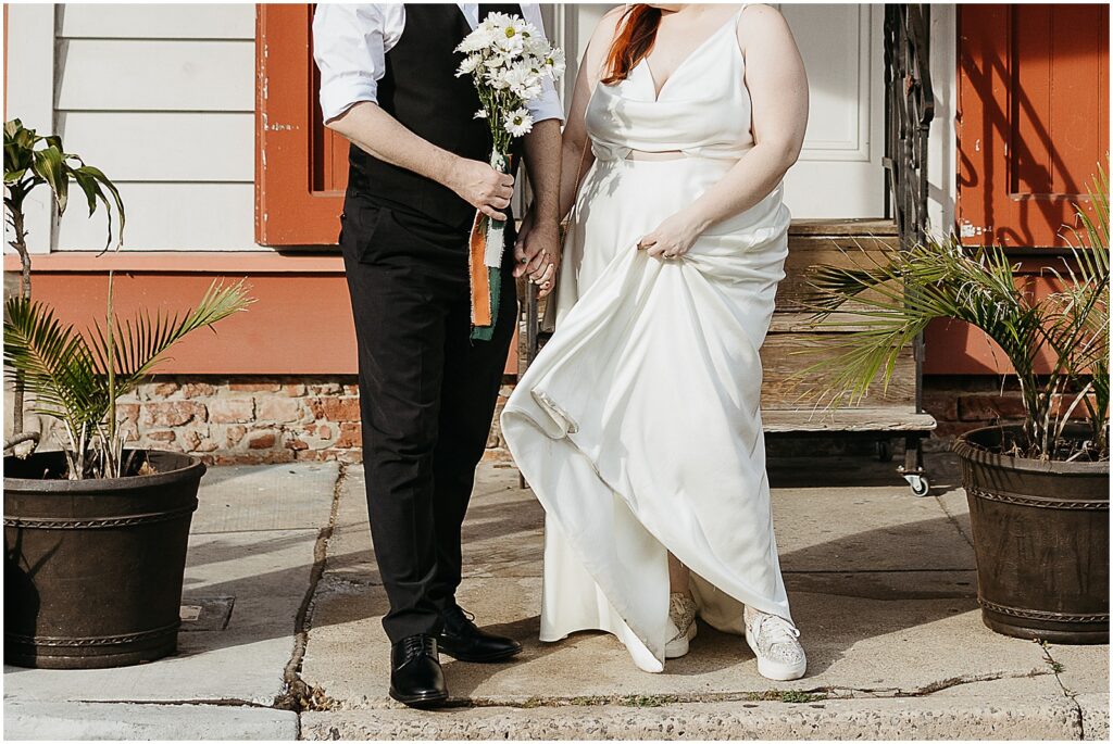 A bride and groom stand on a New Orleans sidewalk.