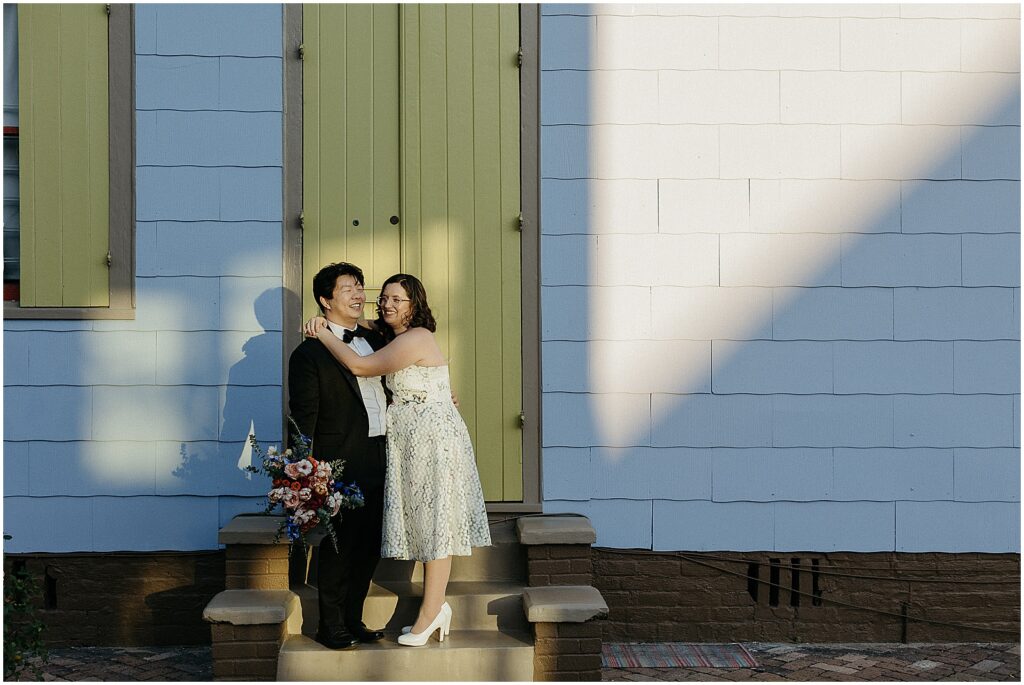 A bride and groom lean on each other on a New Orleans sidewalk after their Capulet wedding.