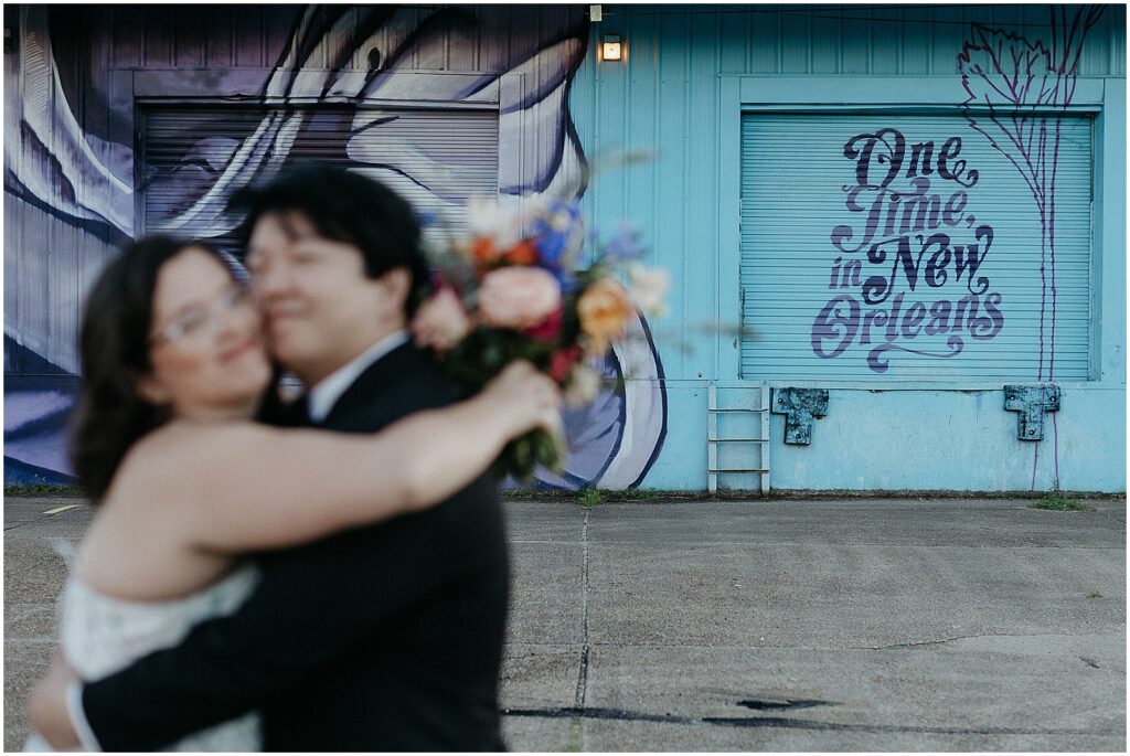 A New Orleans bride and groom embrace in front of a mural in the Bywater.