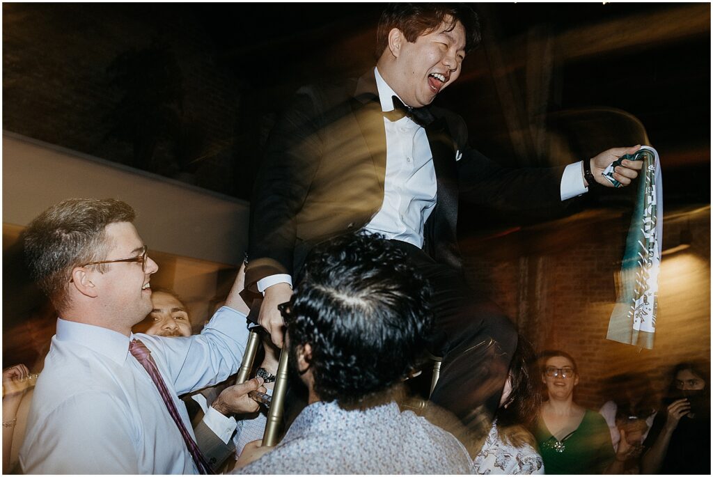 Wedding guests lift Geoff in a chair for the horah.