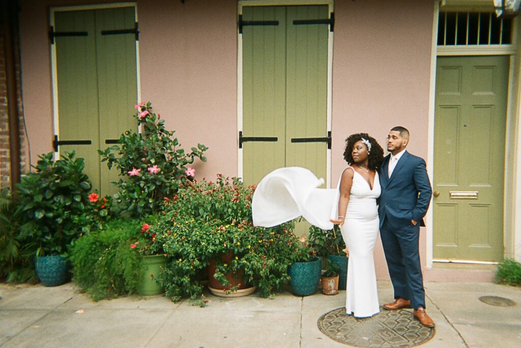 bride and groom elopement film photo in French Quarter in front of colorful building