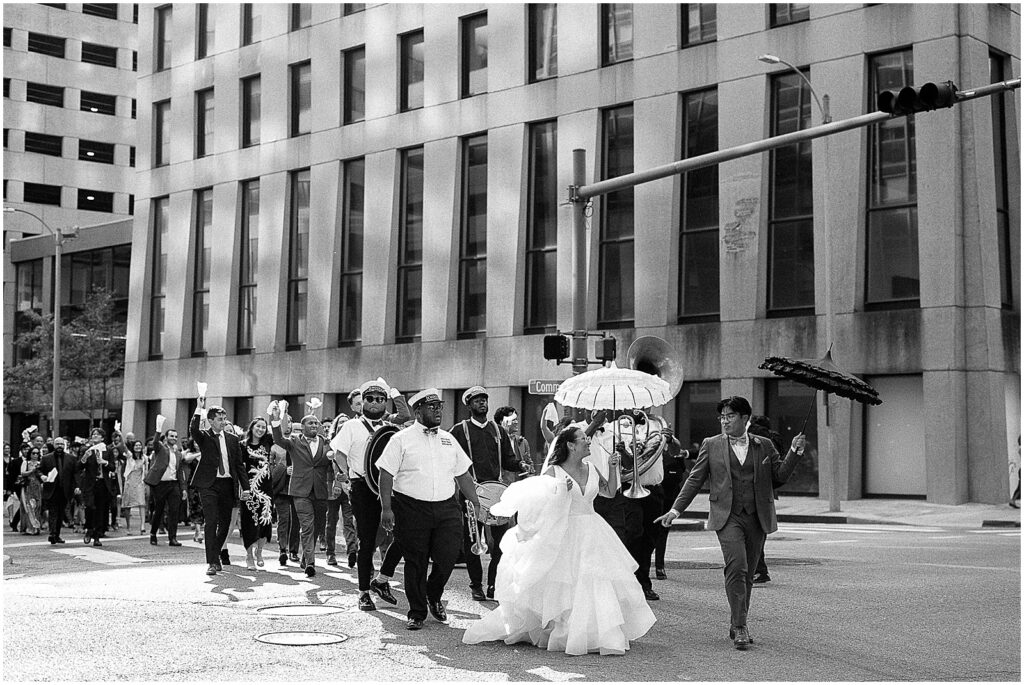 A bride and groom lead a second line through New Orleans' downtown.