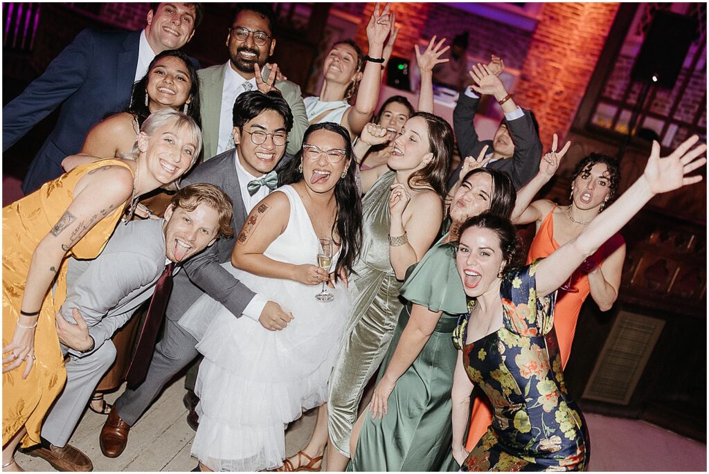 A bride and groom pose with friends on a wedding dance floor.