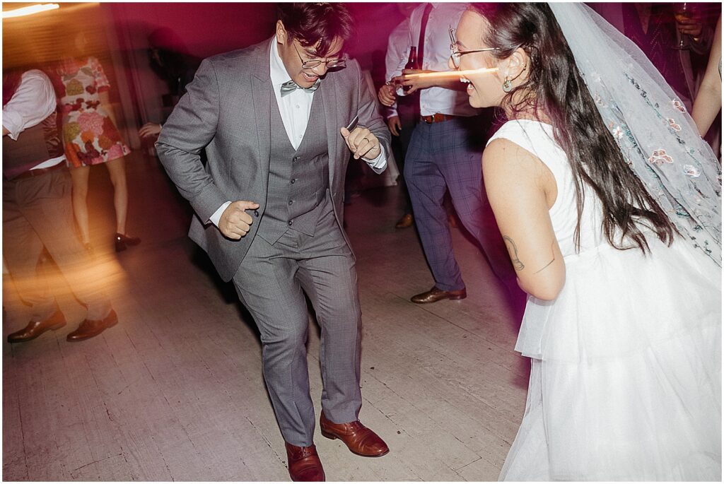 A bride and groom dance and laugh.